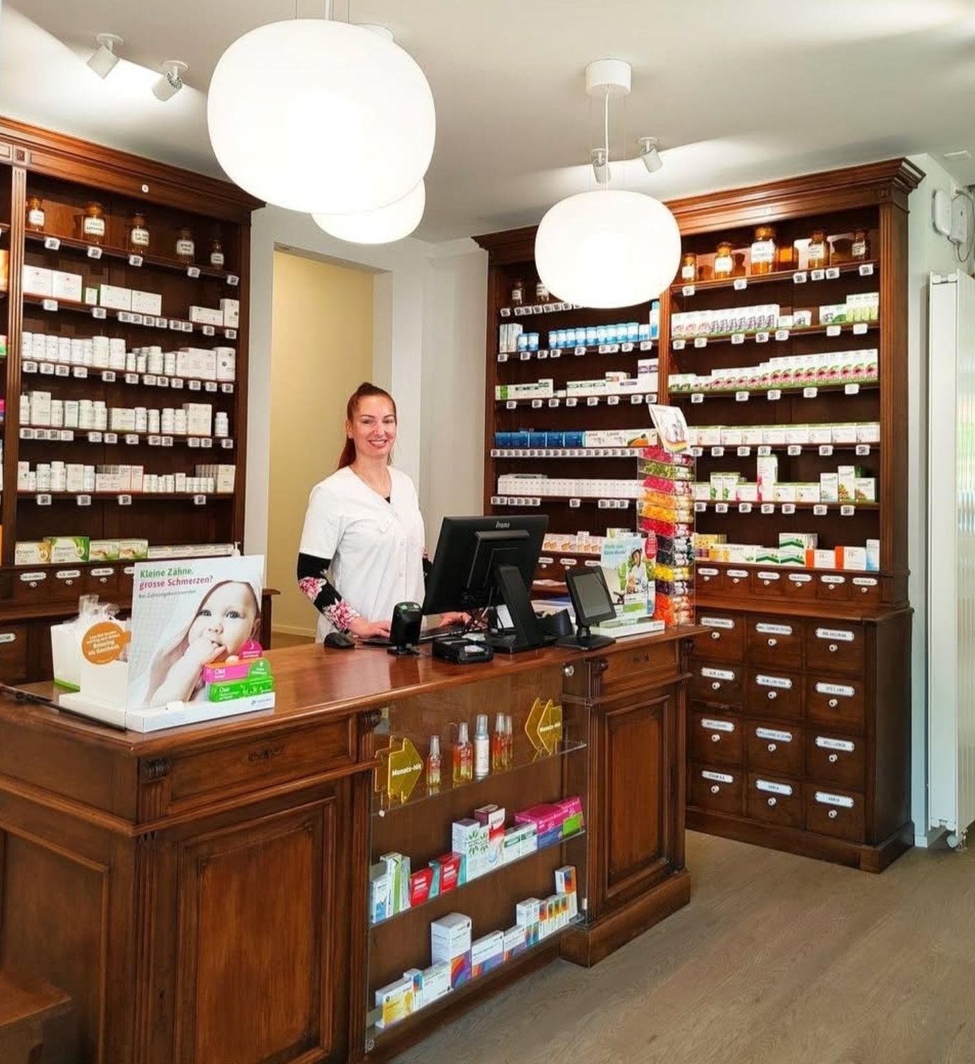 Mitarbeiterin an der historischen Theke der Anklin Apotheke
